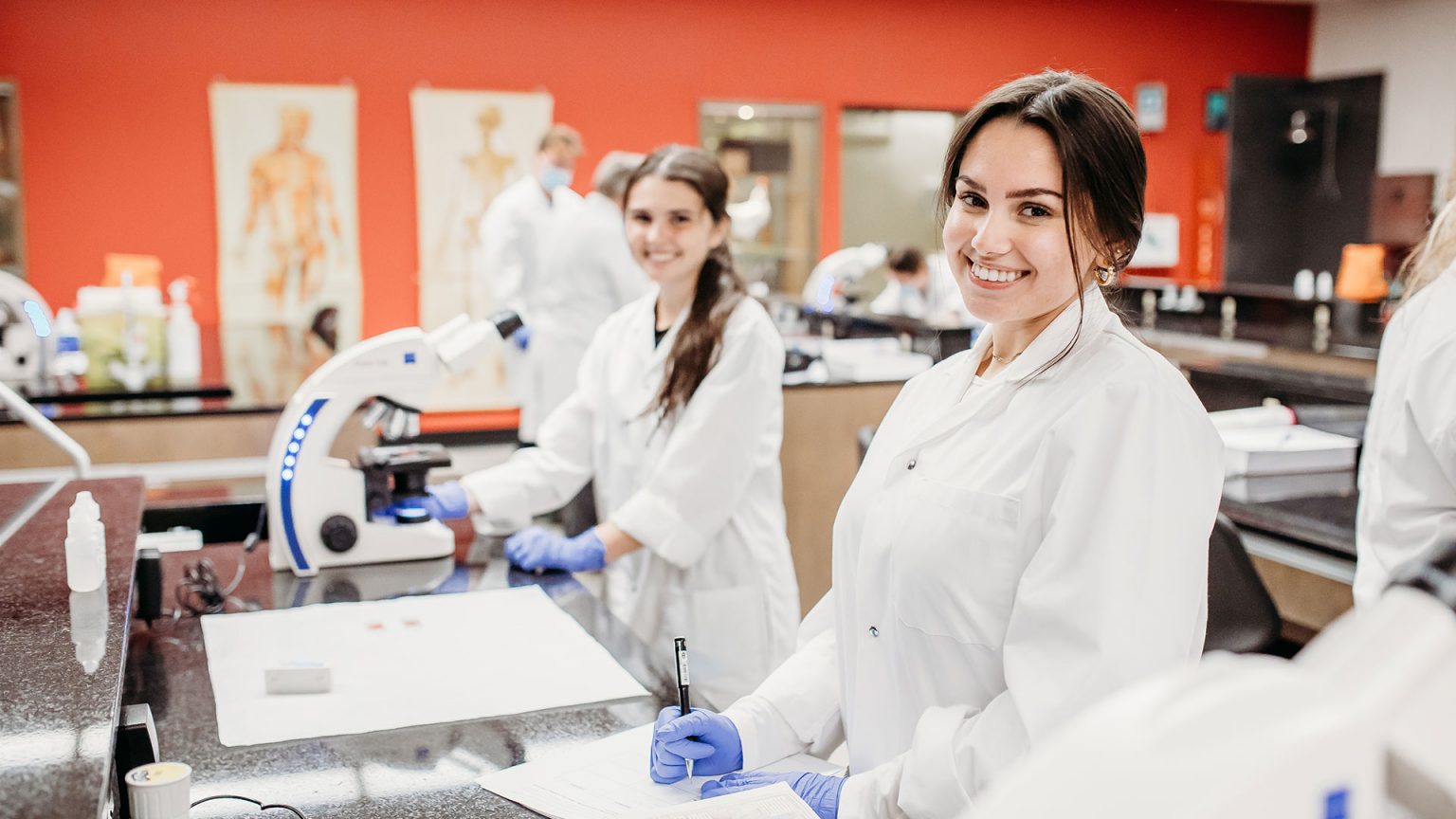 Deux étudiantes souriant à la caméra dans un laboratoire