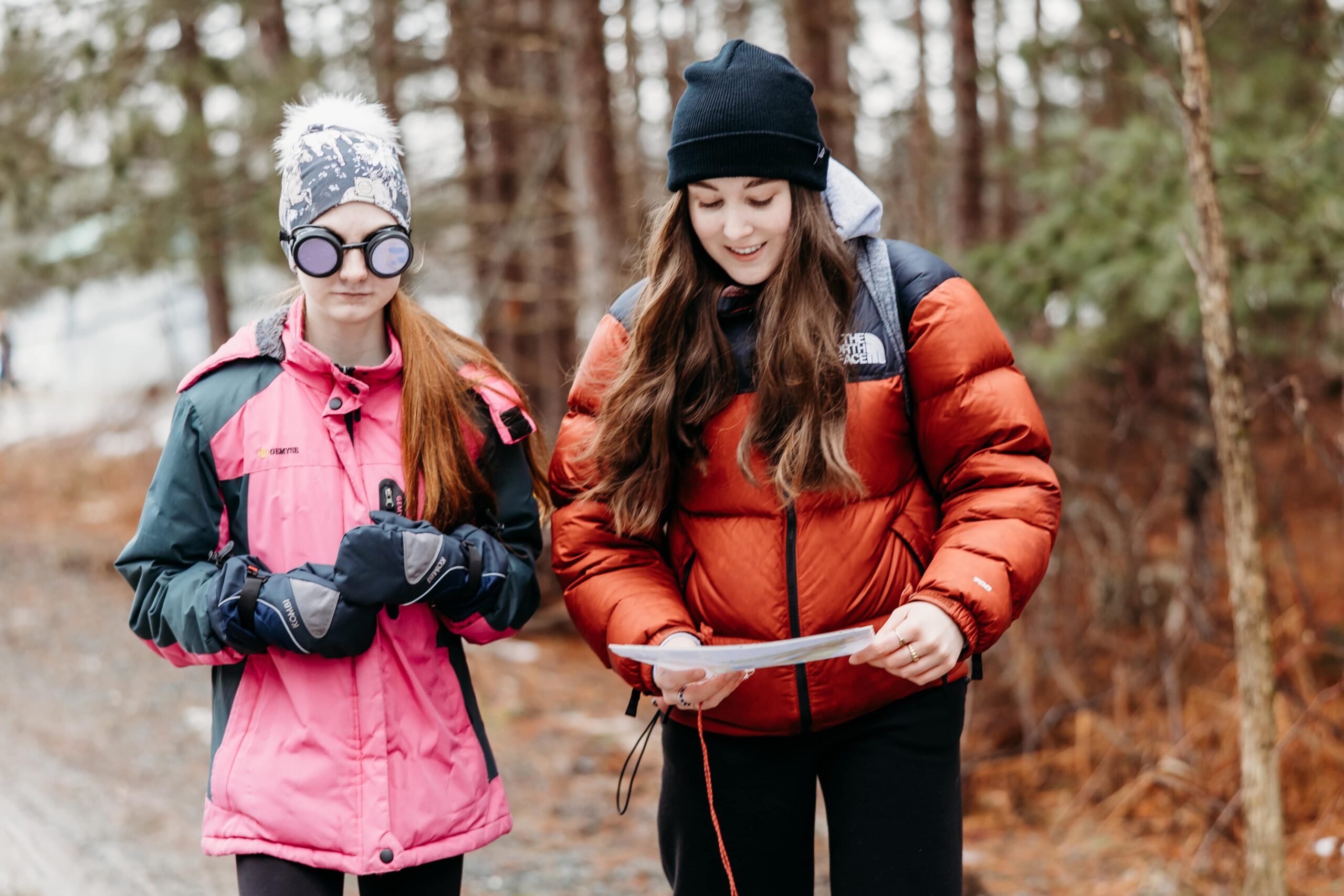 Deux jeunes femmes lisent des papiers en natures. L'une porte des lunettes spéciales dans le cadre d'une expérimentation sociale.