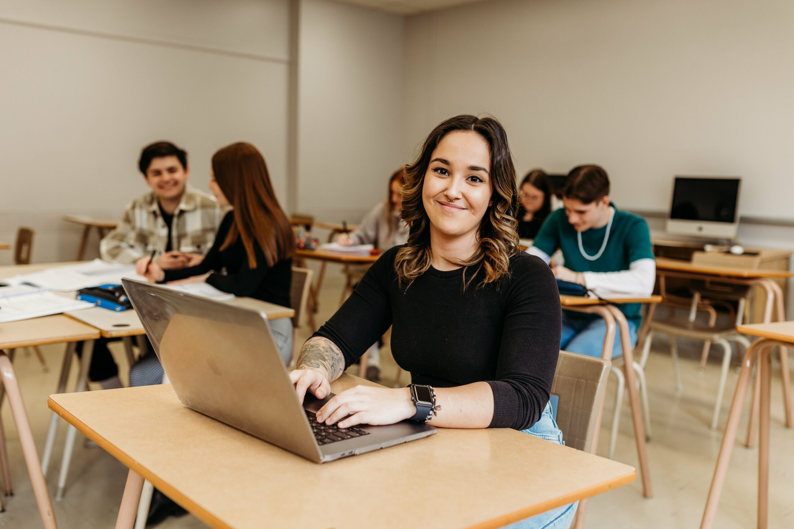Étudiante souriant à la caméra dans une classe.