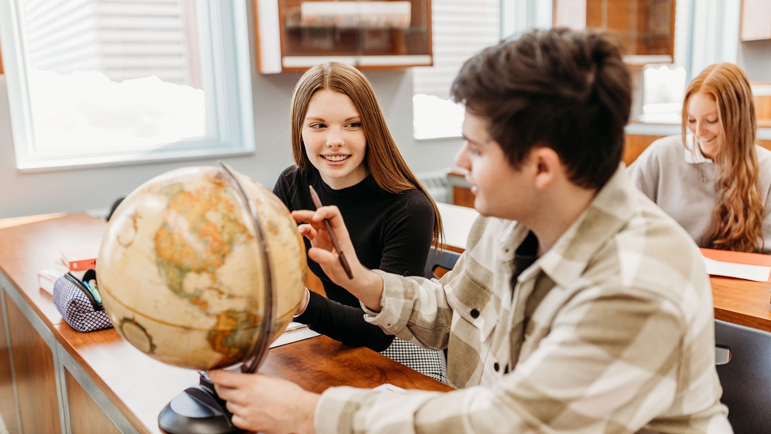 Trois étudiants travaillant à l'aide d'un globe terrestre dans une classe