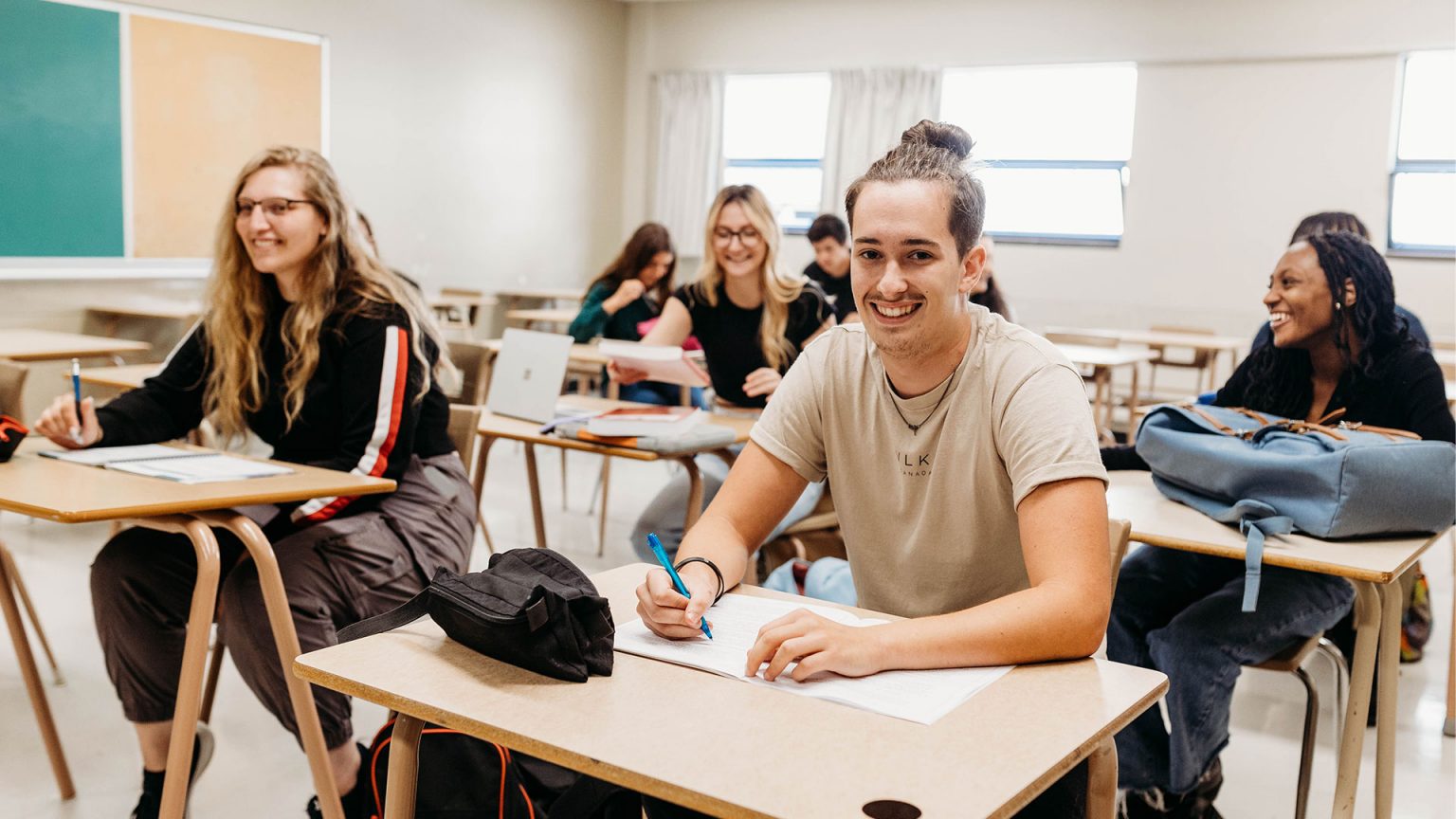 Étudiants souriant à la caméra dans une classe