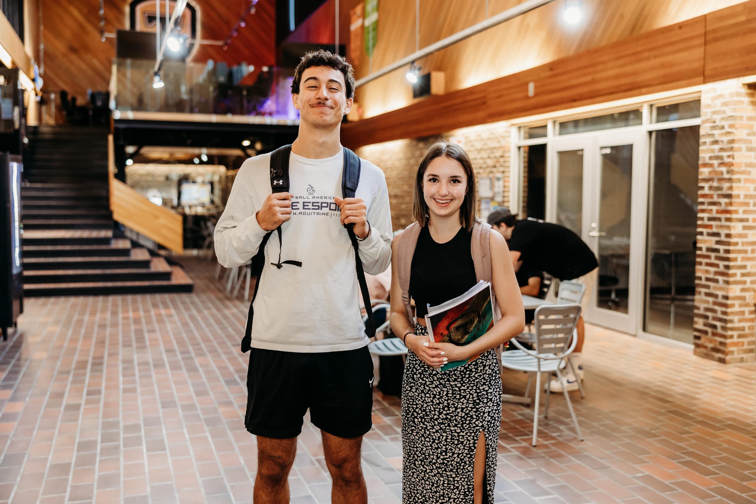 Deux jeunes étudiants sourient à la caméra dans un espace commun du Cégep de Thetford.