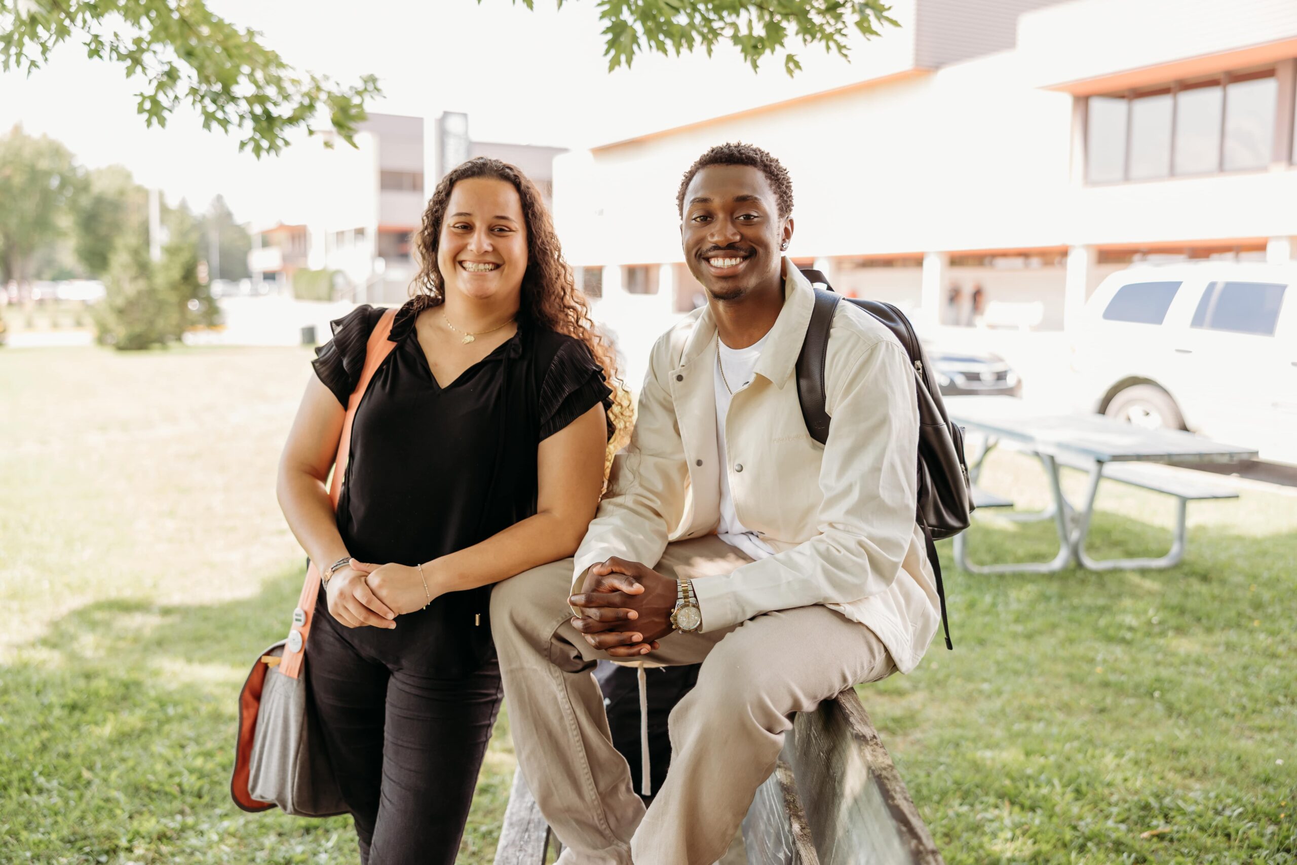 Deux étudiants sourient à la caméra à l'extérieur.