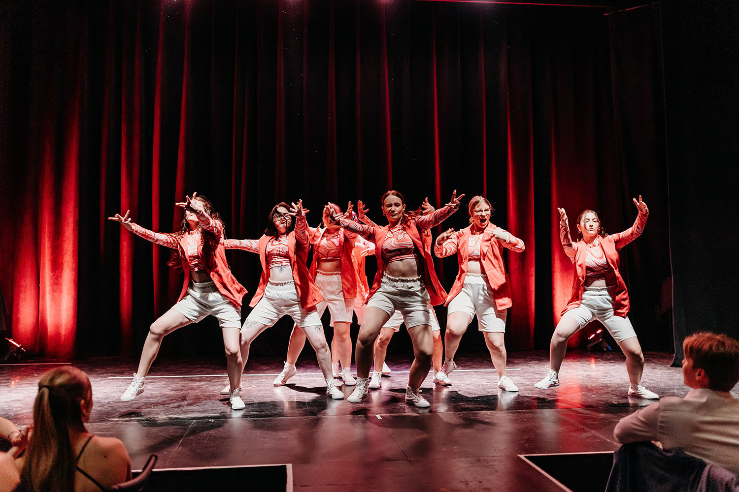 Photo croquée sur le vif d'une troupe de dance en plein spectacle. Les artistes portent des vêtements urbains hip-hop rouge et beige.