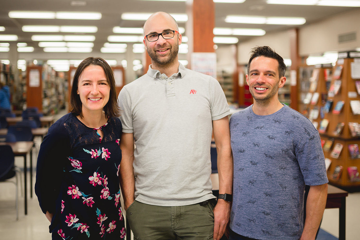 Trois jeunes professionnels regardent la caméra en souriant dans la bibliothèque du Cégep de Thetford.