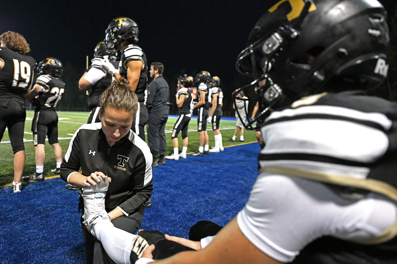 Une physiothérapeute sportive assiste un athlète de football lors d'une partie