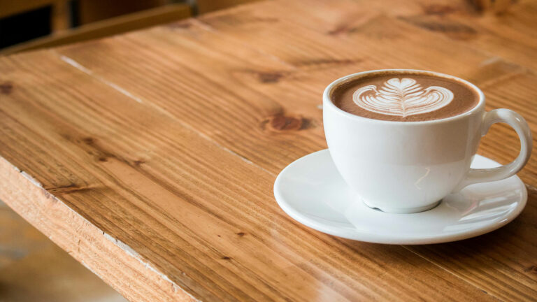 Gros plan sur une table en bois avec un café latté.
