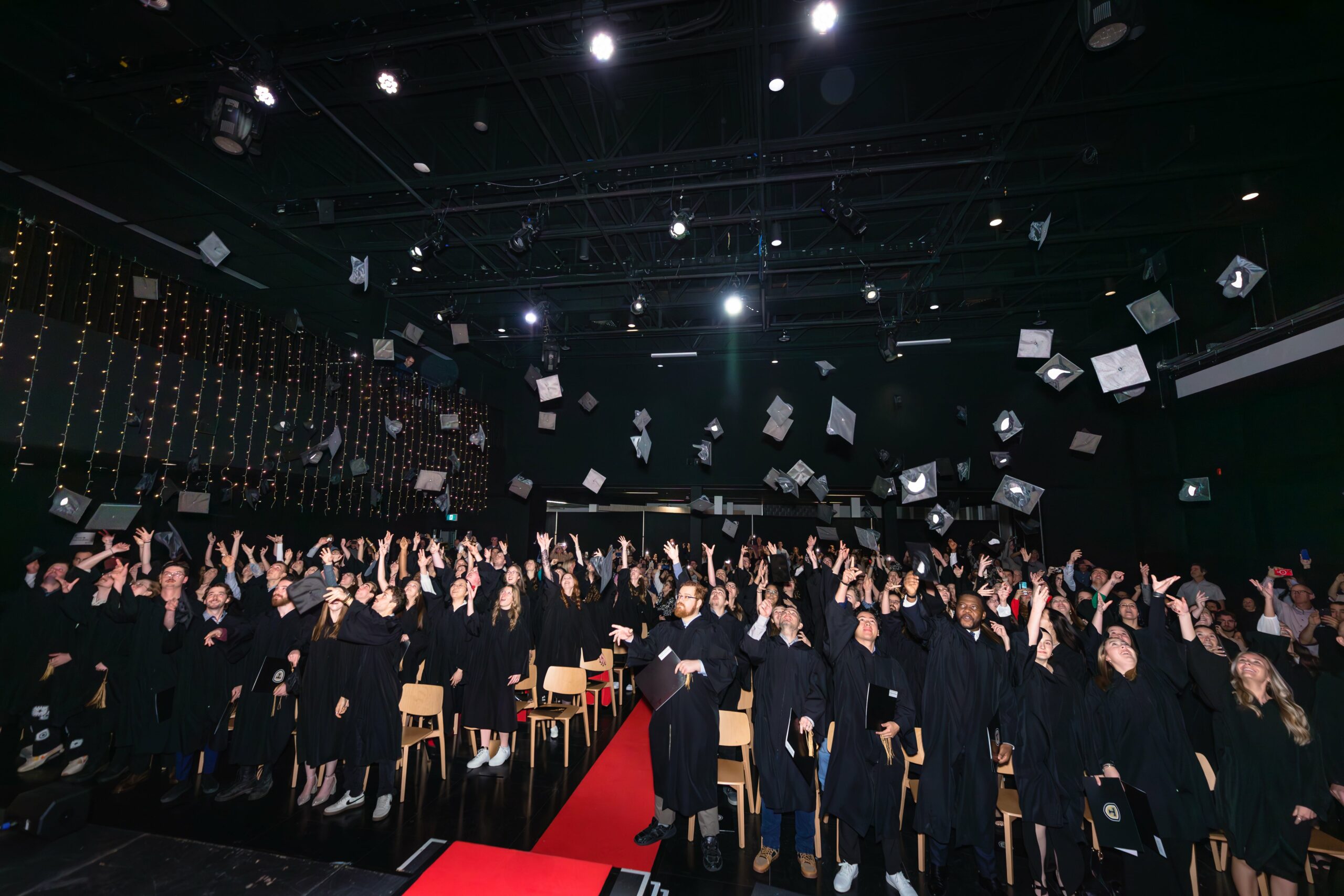 Des étudiants gradués lancent leur chapeau dans les airs.