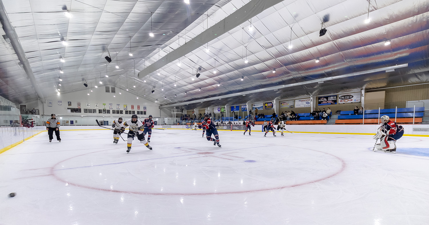 Deux équipes de hockey sont en mouvement sur la patinoire.
