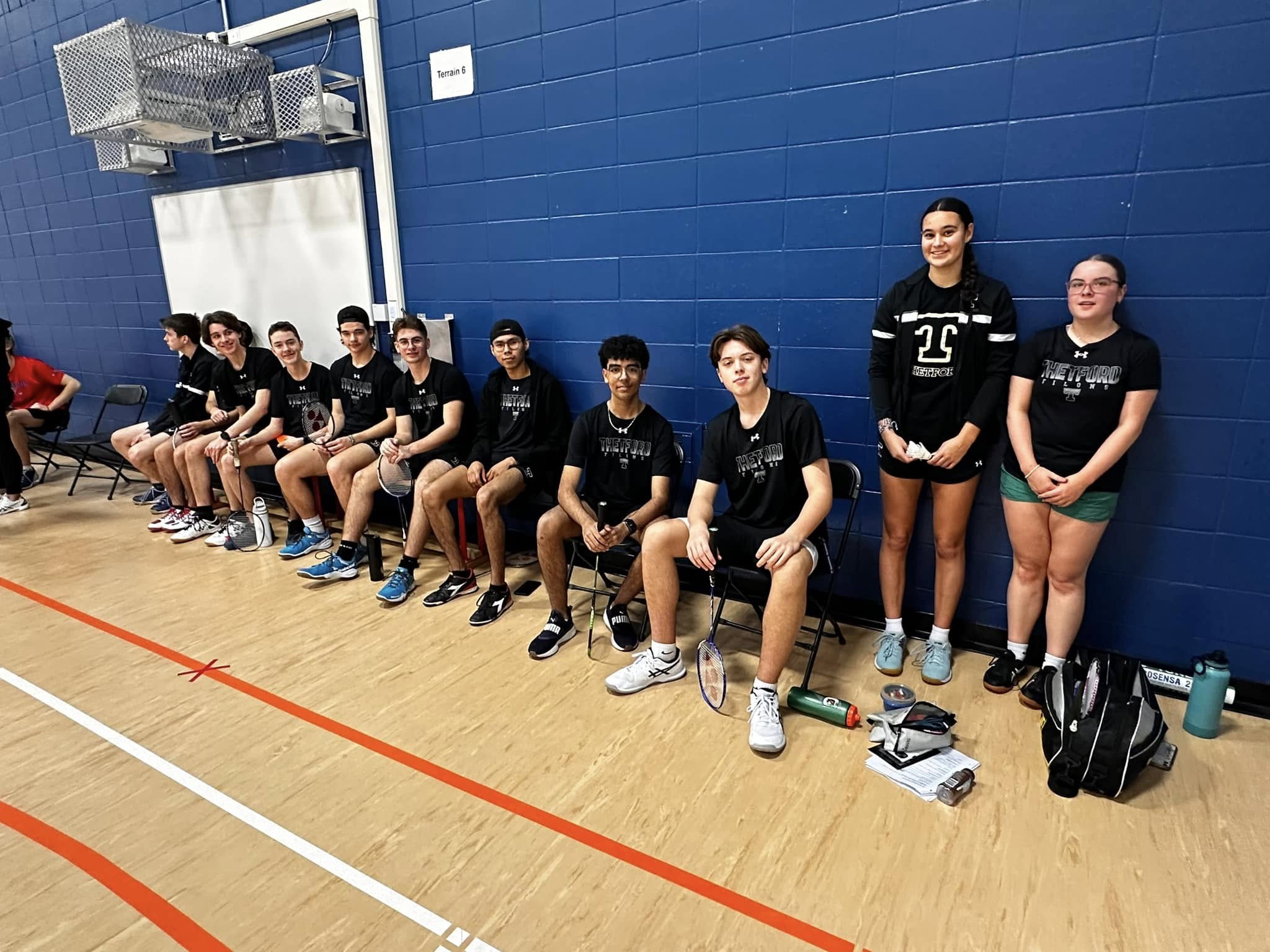L'équipe de badminton sourit à la caméra.