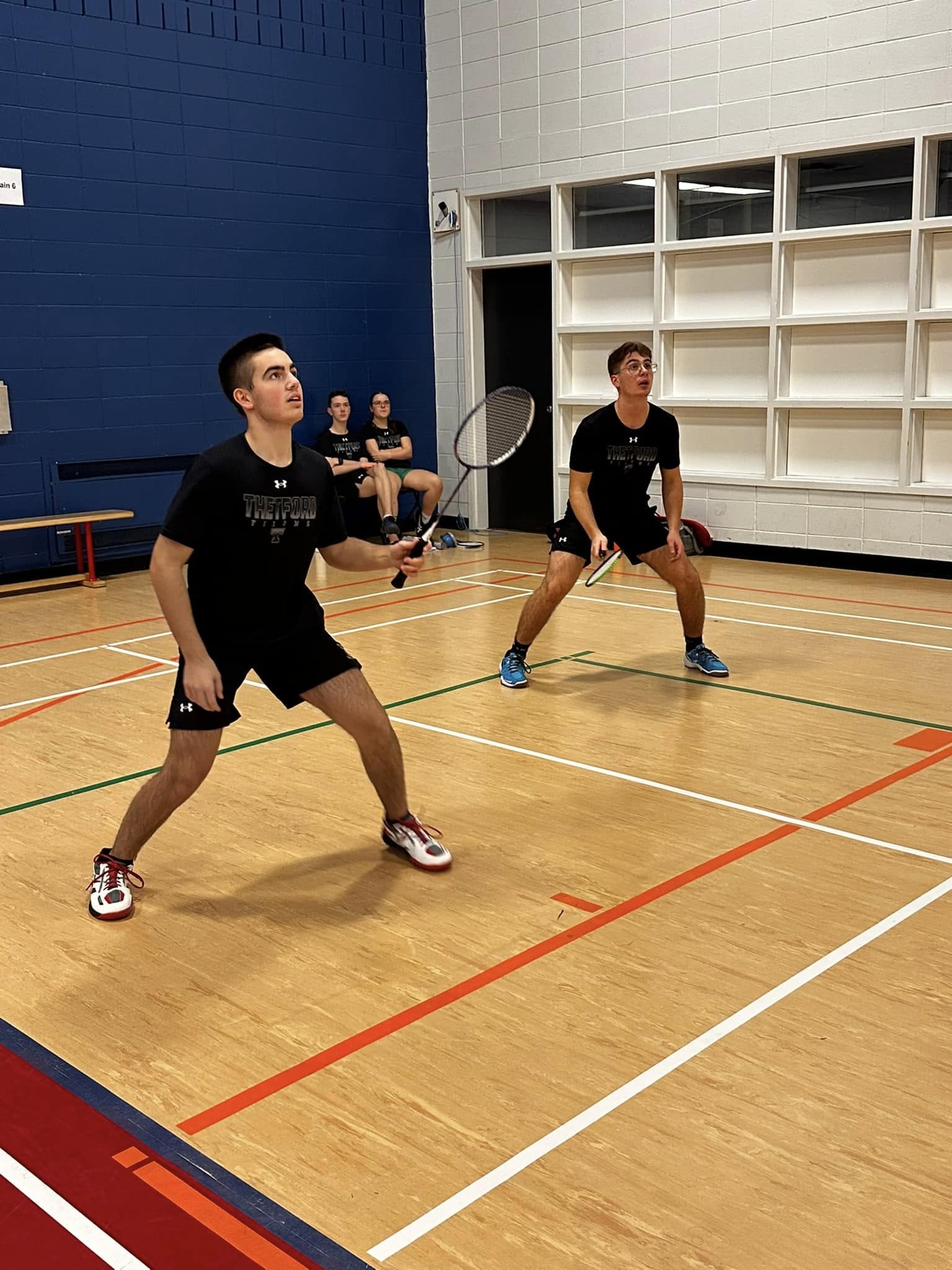 Deux joueurs de badminton se préparent à recevoir le volant.