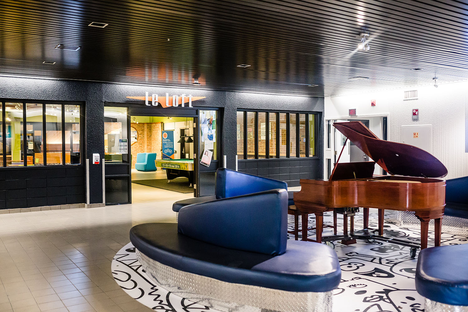 Un espace est aménagé avec des divans et un piano.