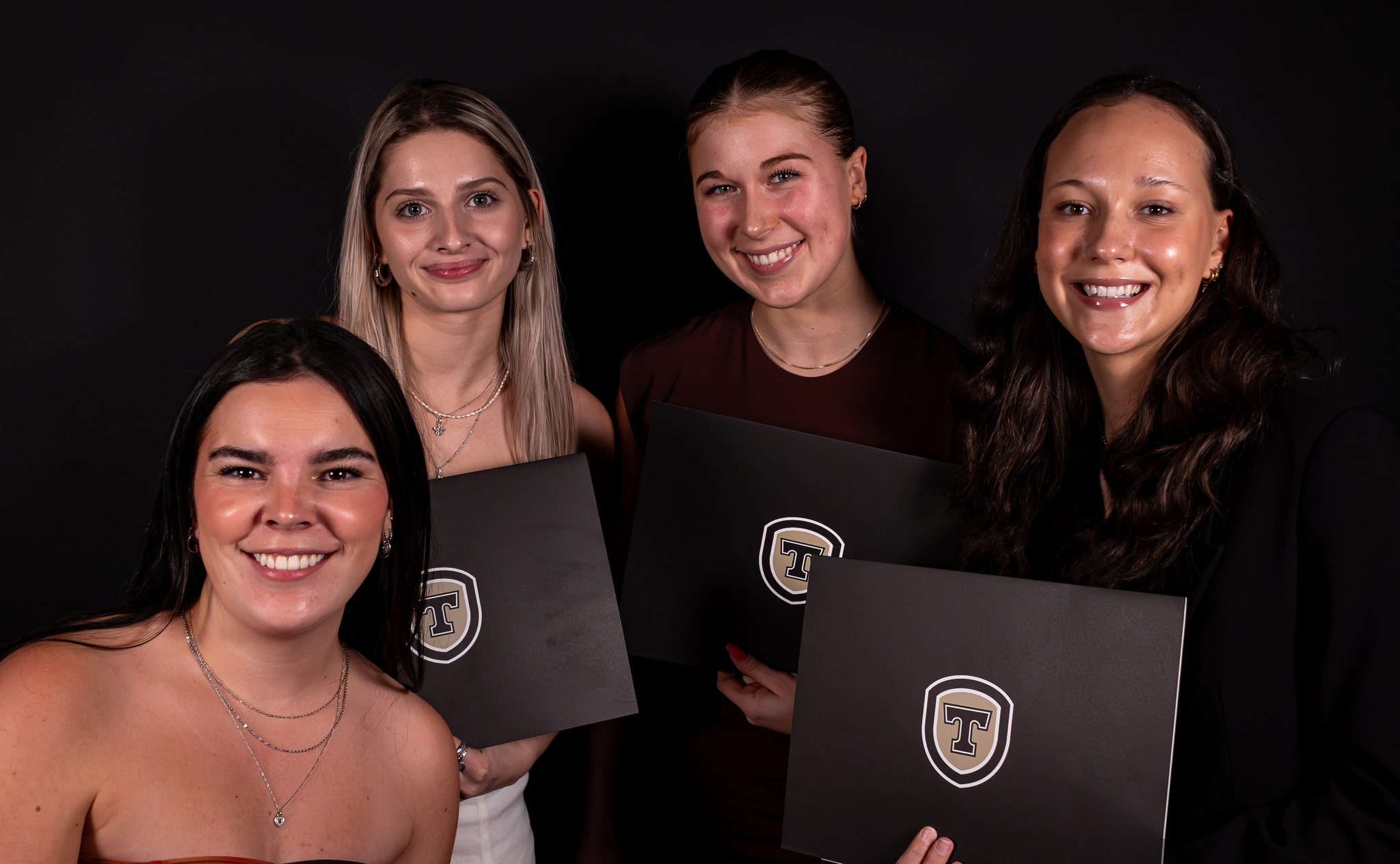 Quatre étudiantes tenant leur diplome de gala.