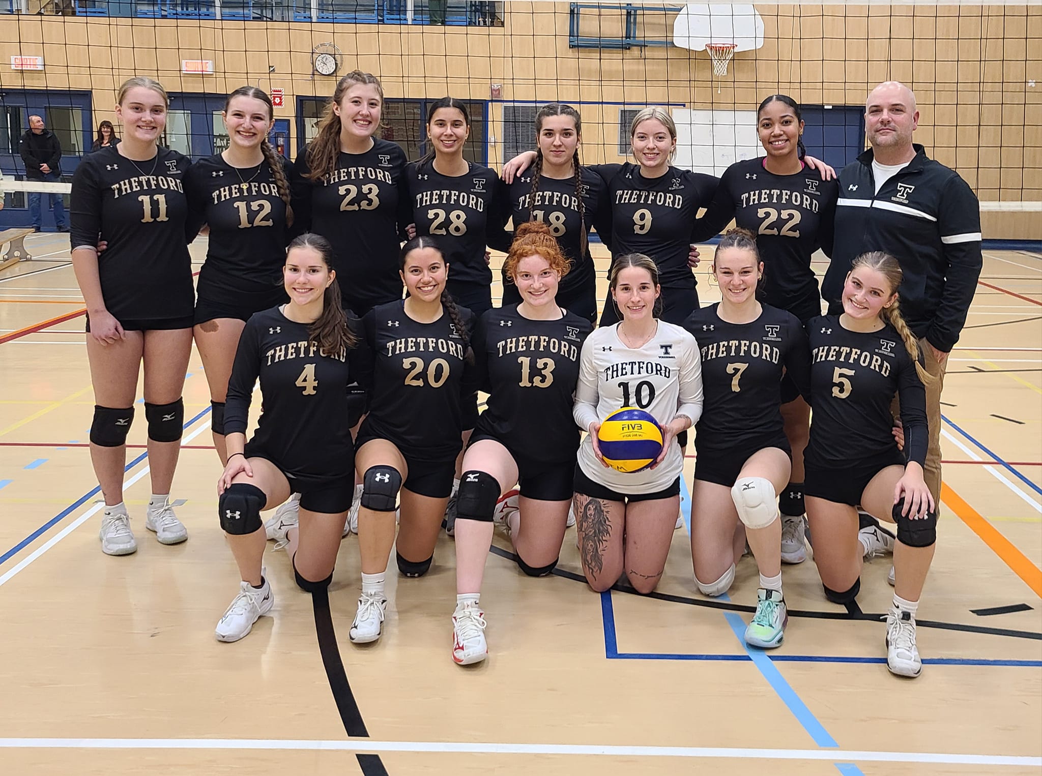 L'équipe féminine de volleyball sourit à la caméra.